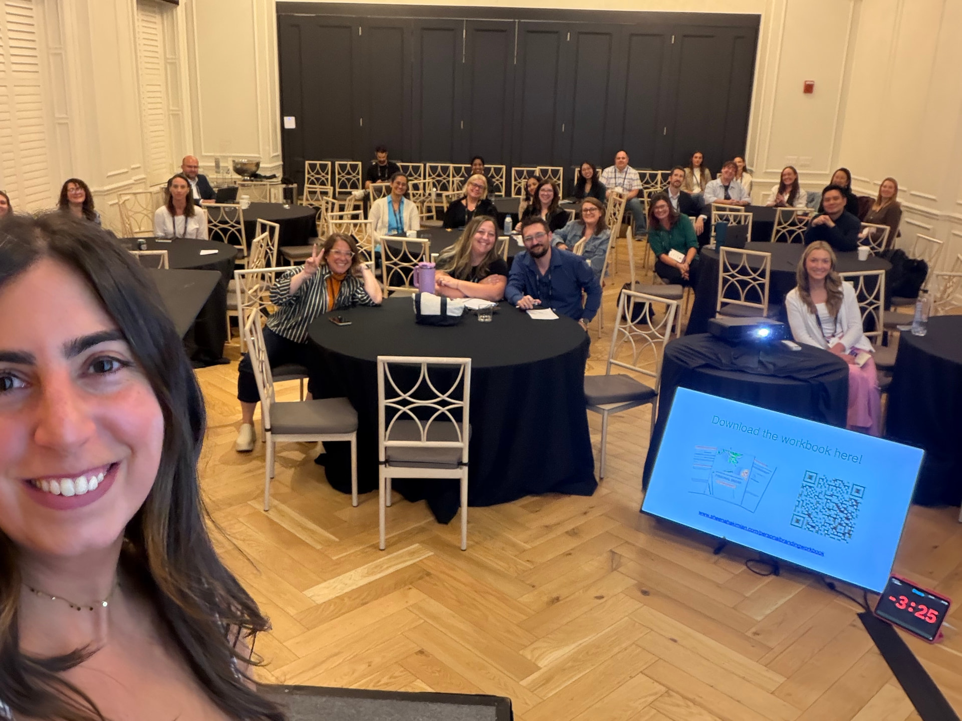 Sheena taking a selfie with a smiling workshop audience behind her