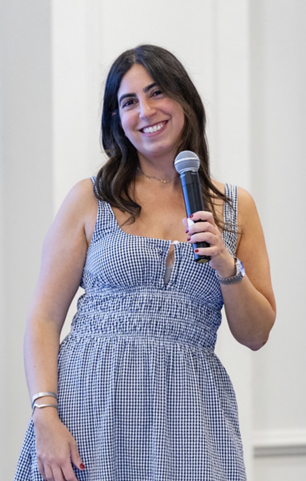 Sheena smiling and holding a microphone while speaking